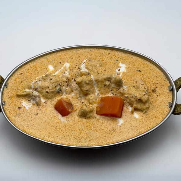 Creamy Indian chicken curry with red bell peppers, served in a metal bowl.