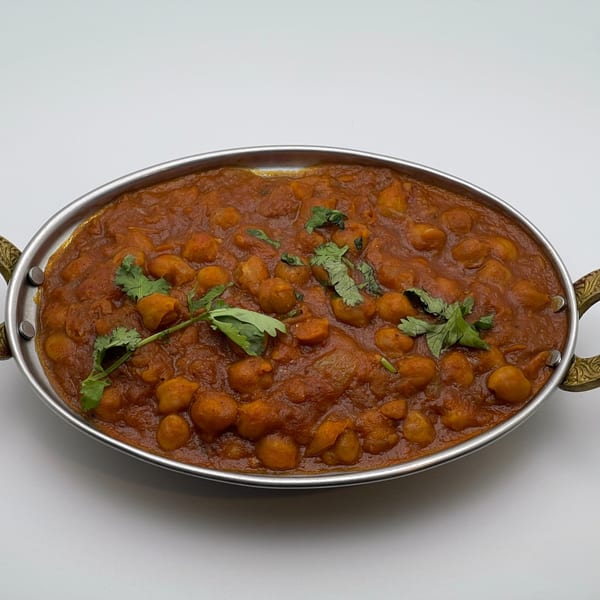 Chana Masala, an Indian chickpea curry, garnished with fresh cilantro in a metal serving dish.