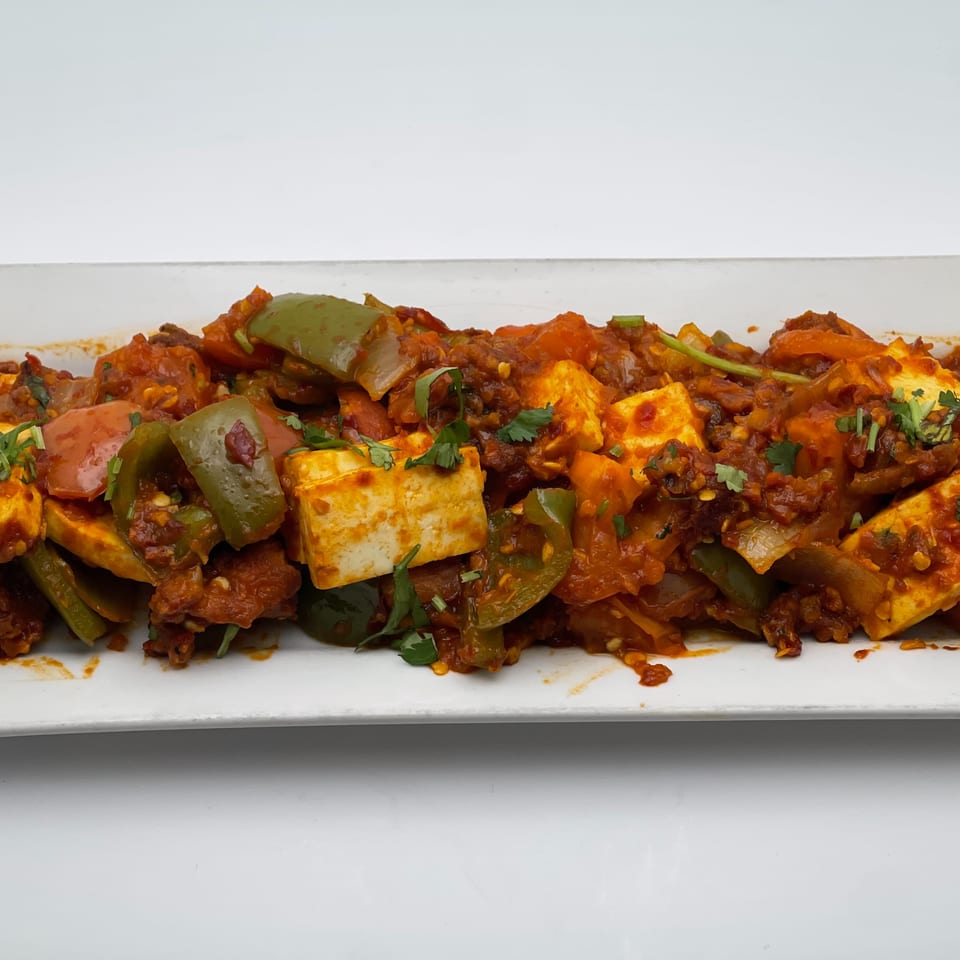 Indian Palace's chili paneer, a vibrant dish with paneer, bell peppers, and spices on a white platter.