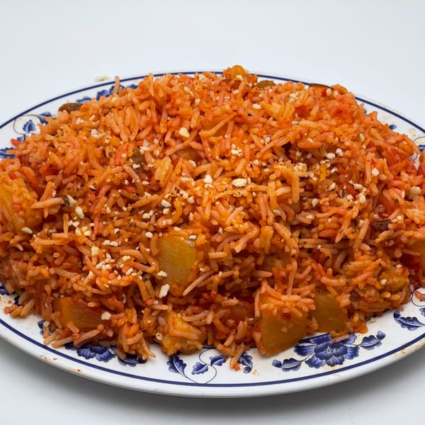A vibrant orange Indian rice dish with nuts and pineapple chunks, served on a white and blue plate.