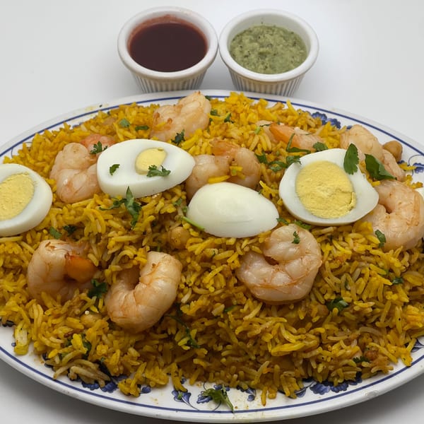 Shrimp biryani with hard-boiled eggs and cilantro, served with two dipping sauces at India Palace.