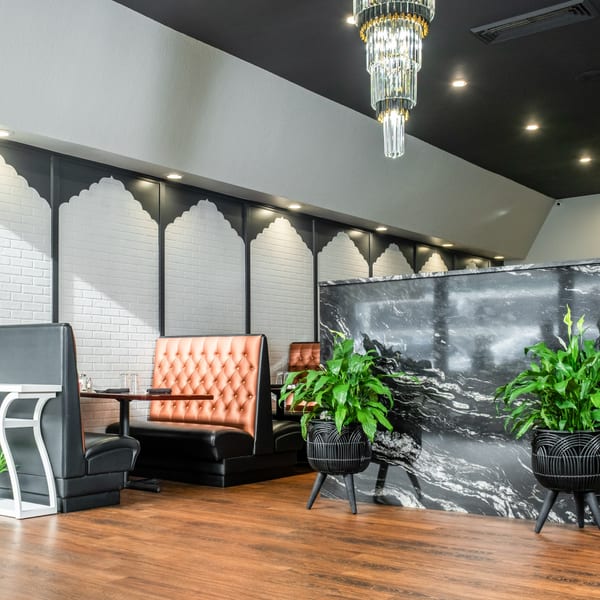 India Palace dining area with black and orange booths, a marble counter, and decorative archways.