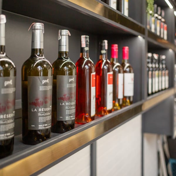 Wine bottles, including "La Réserve" and red wines, displayed on dark shelves at India Palace.