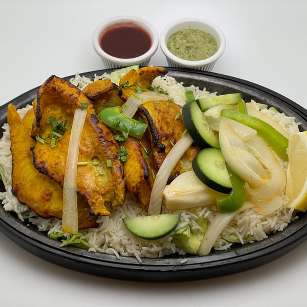 Indian Palace chicken tikka with rice, vegetables, and two dipping sauces in a black container.